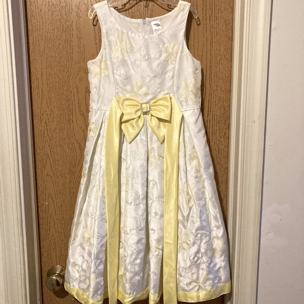 White embroidered dress with yellow flowers and green leaves.